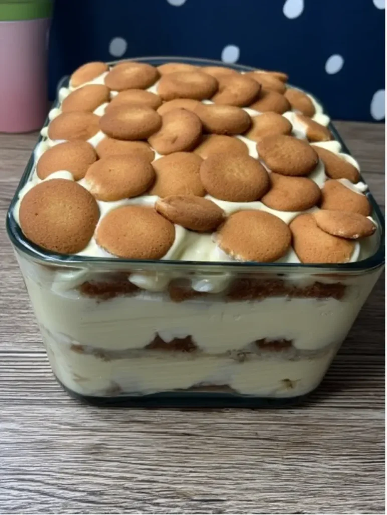 Southern banana pudding in glass dish with wafers and cream.